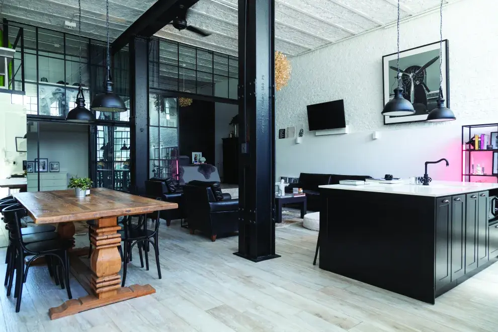 La mesa de madera corta con lo industrial del negro y el blanco de la caja arquitectónica. LA LUZ ROSA (@bronx.concept) otorga un toque original.