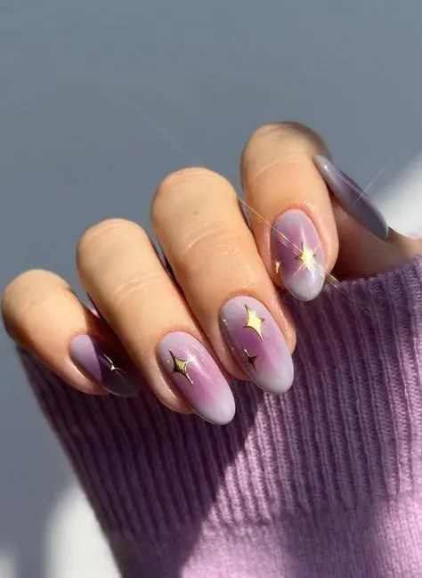 Uñas aura con apliques de estrellas doradas. Un diseño muy astrológico.