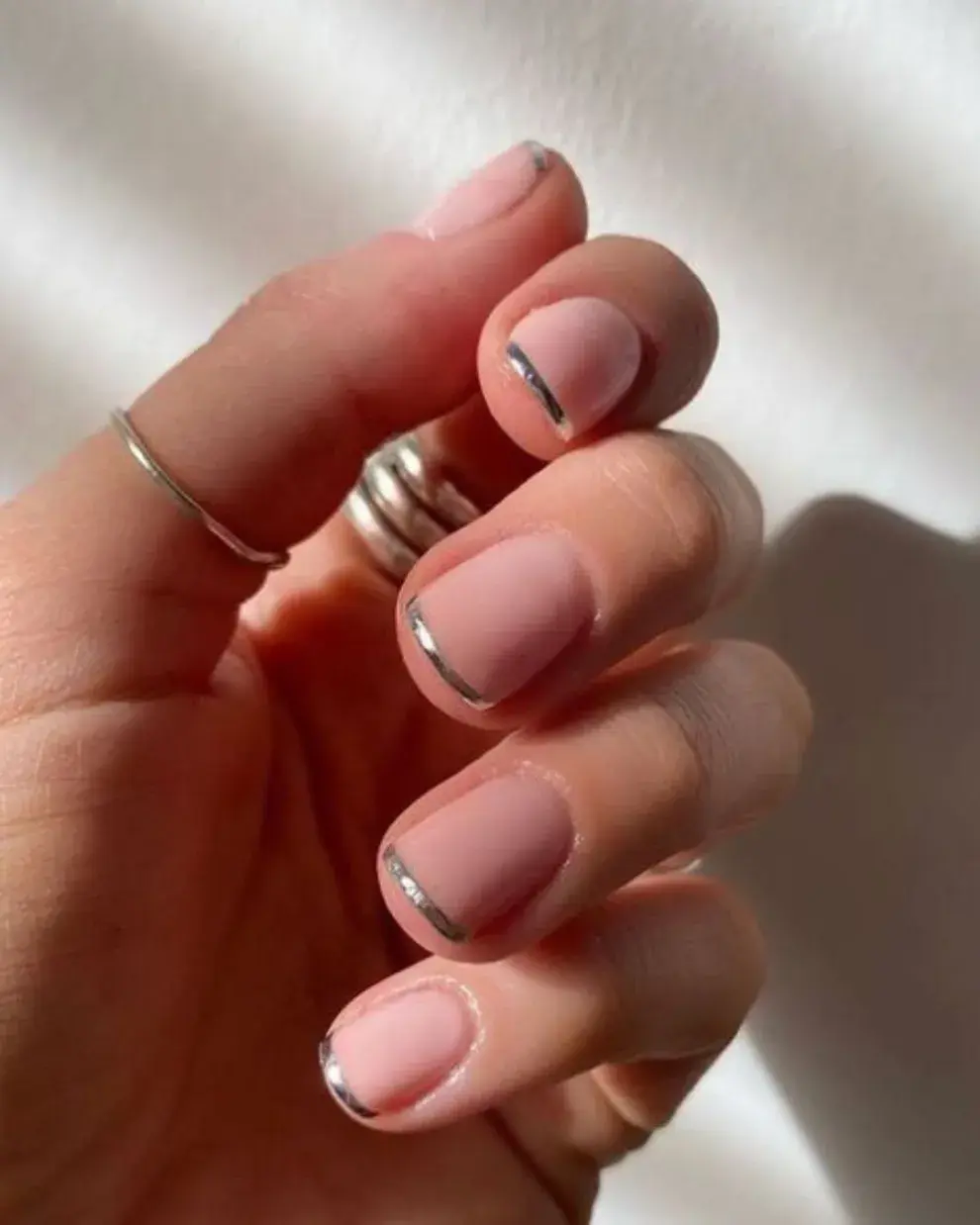 Un diseño de uñas bien cortas, con manicura francesa pero reemplazando el esmalte blanco por uno plateado. Clásicas pero con toque distinto.