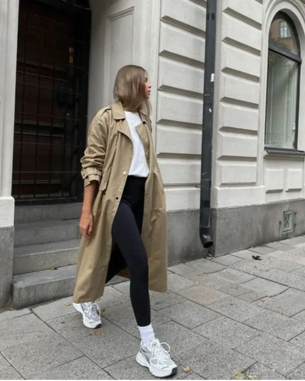 Con trench coat, zapas blancas y medias a la vista.