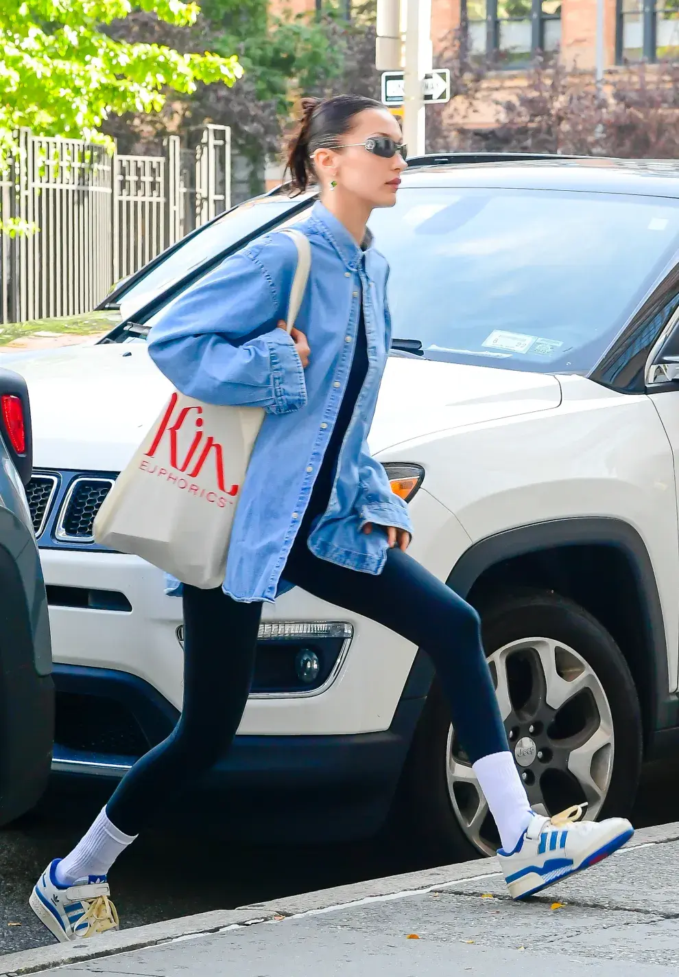 Bella Hadid con un look en el que prendas de entrenamiento se combinan con una camisa de denim. 