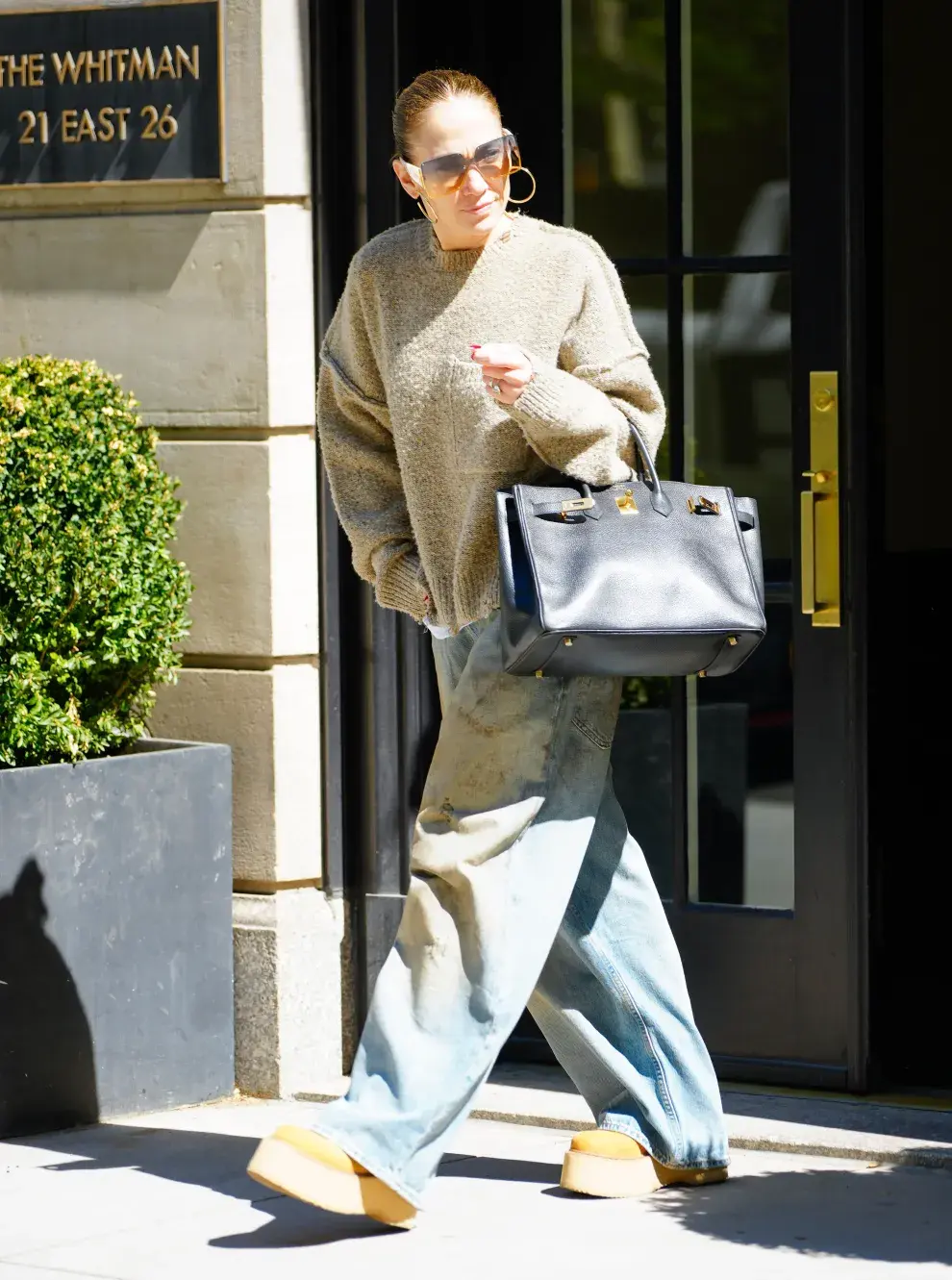 JLo en las calles de Nueva York con un outfit estilo comfy. Sweater crop oversize, jean ancho y abotinados con plataforma. 