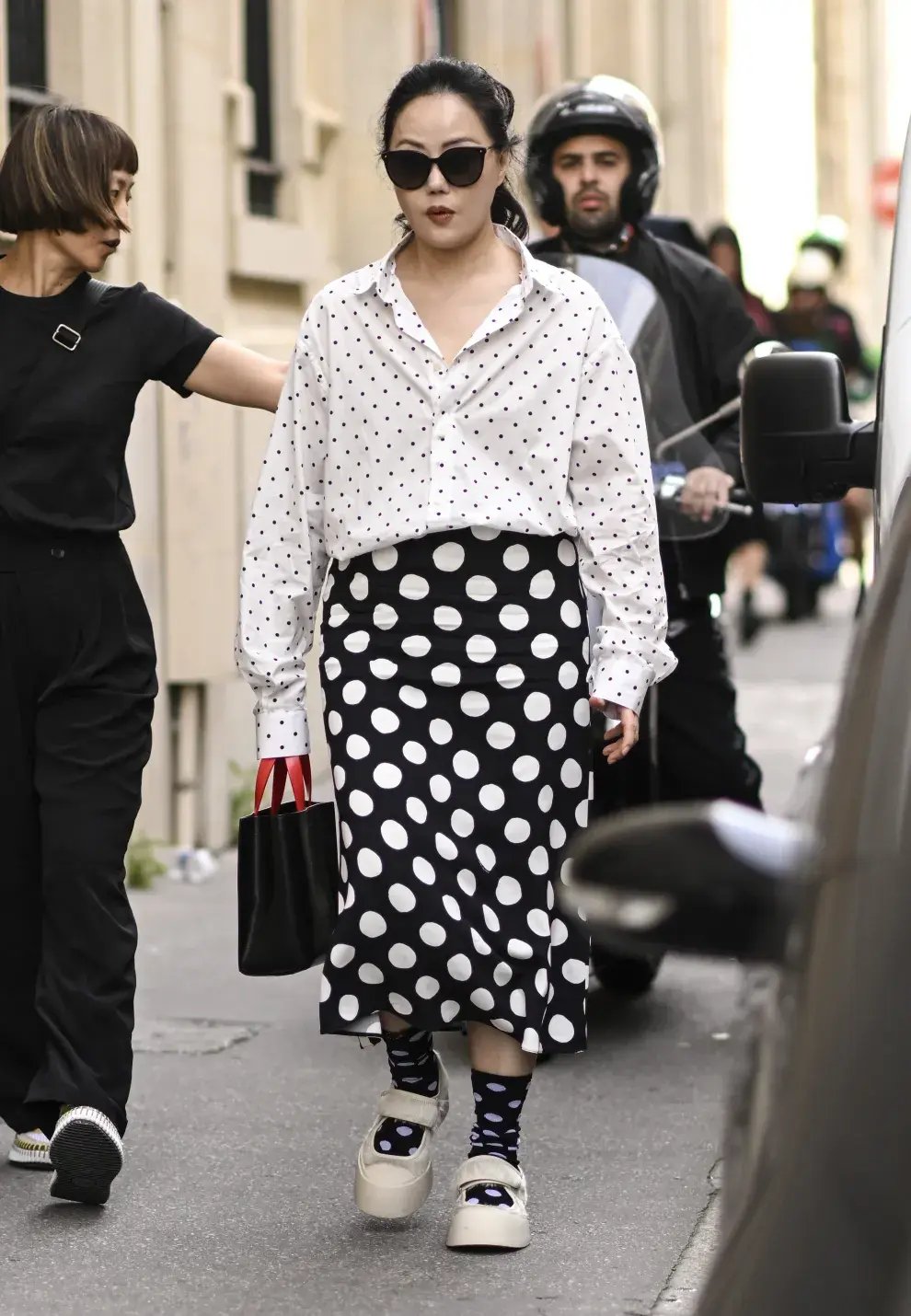 Mujer con camisa y falda a lunares por la ciudad.