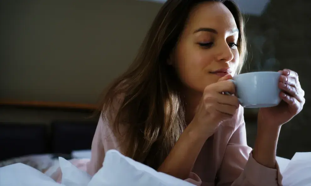 mujer tomando un té en la cama.