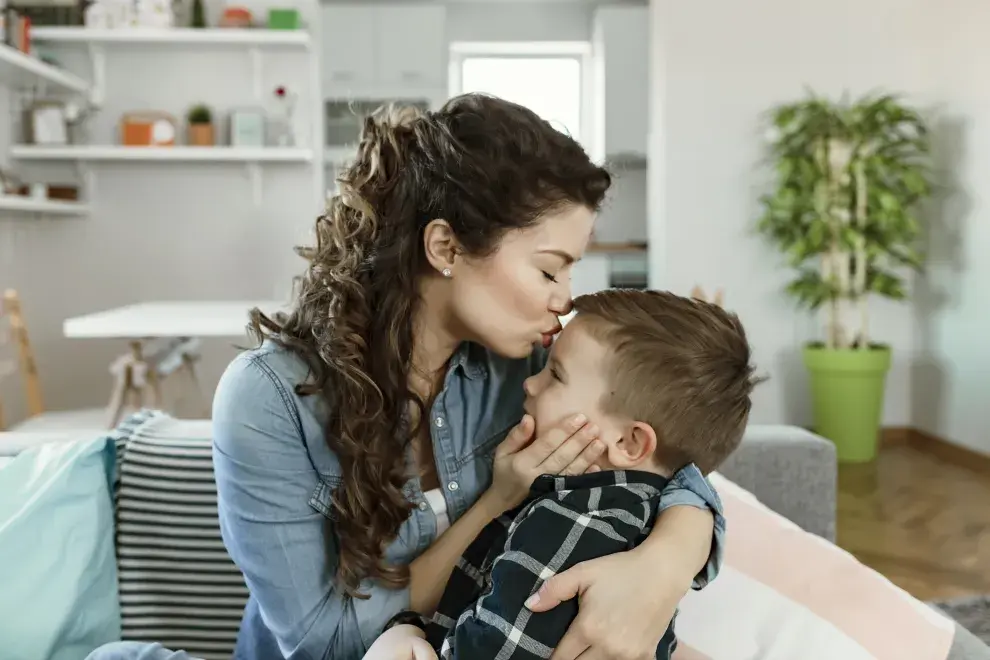 ¿Madre helicóptero? Madre abraza y besa a su hijo.