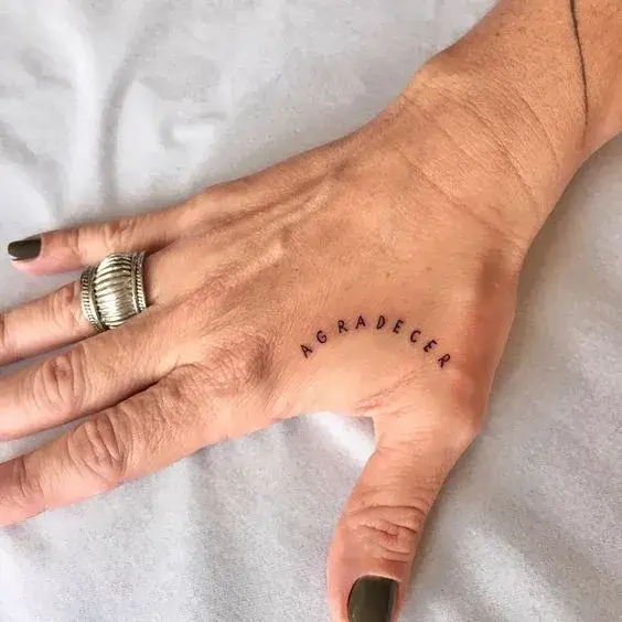 tatuaje en la mano que dice "agradecer"