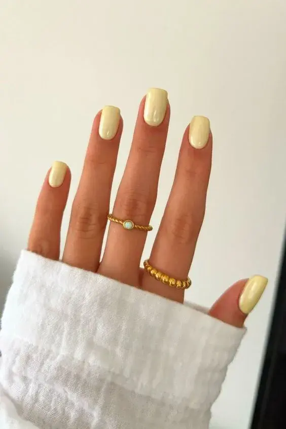 Foto de una mano con uñas en color amarillo.