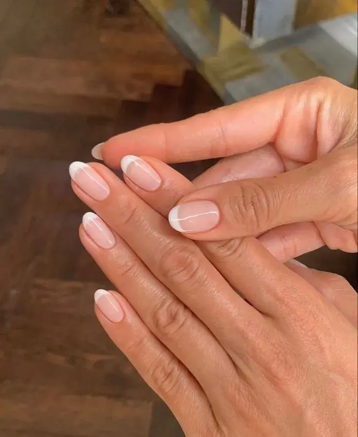 Foto de dos manos con esmalte de uñas blanco.