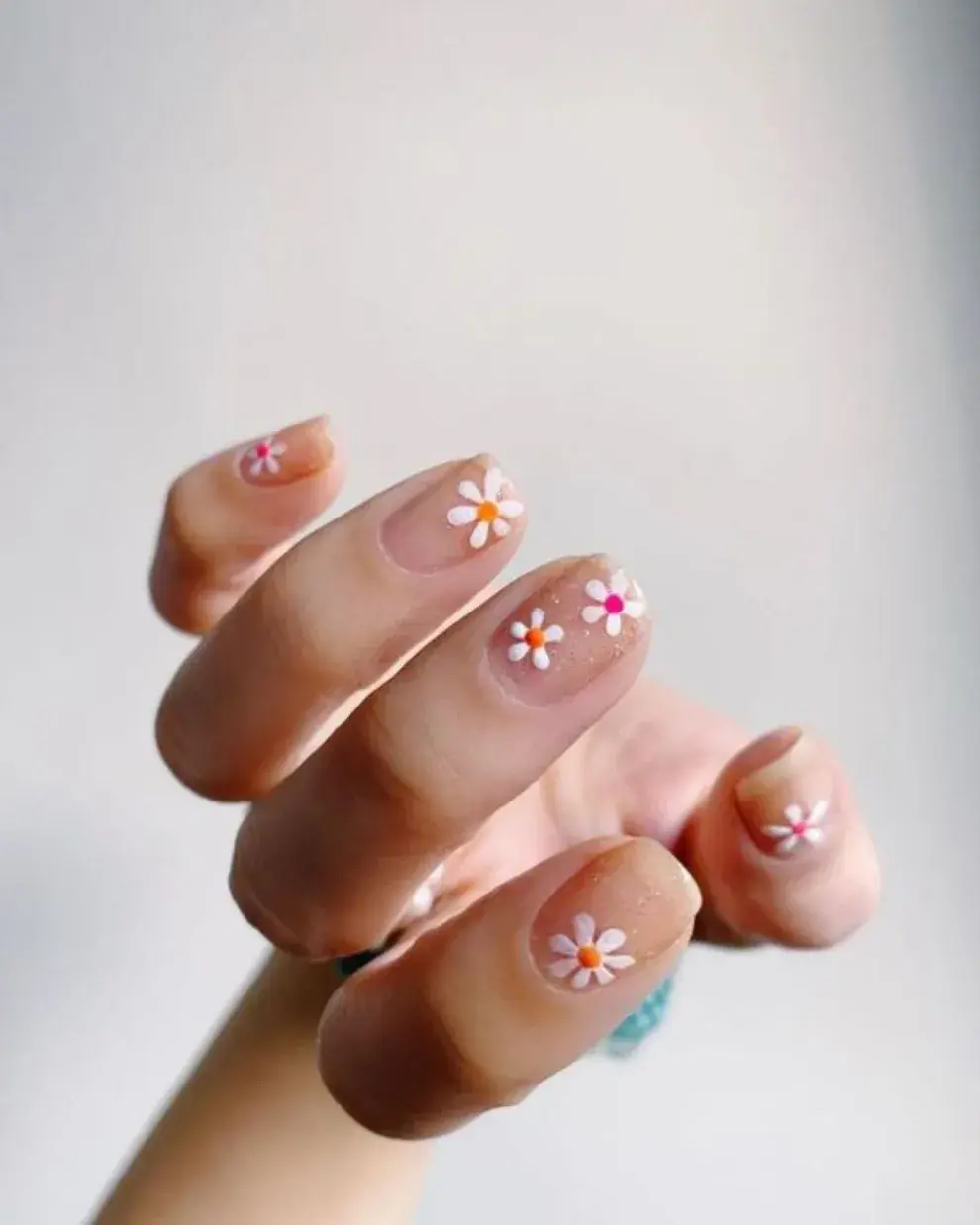 Foto de una mano de mujer con nail art de margaritas.