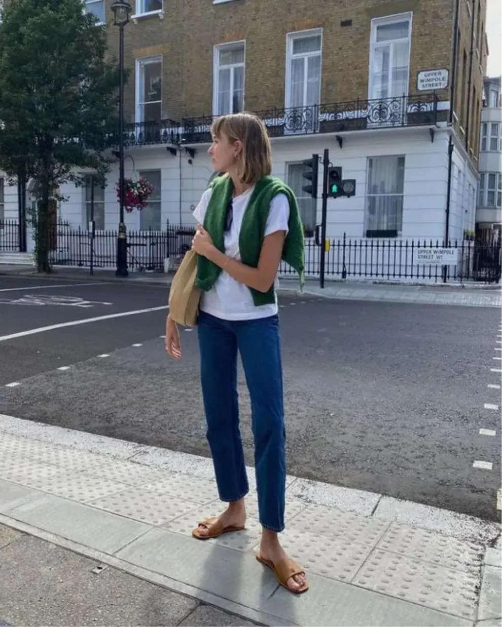 Foto de una mujer en la calle usando un suéter al hombro.