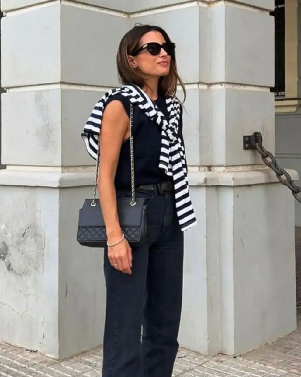 Foto de una mujer en la calle usando un suéter al hombro.