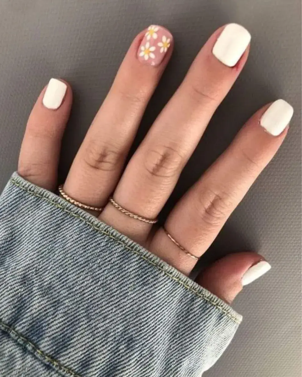  Foto de una mano de mujer con nail art de margaritas.