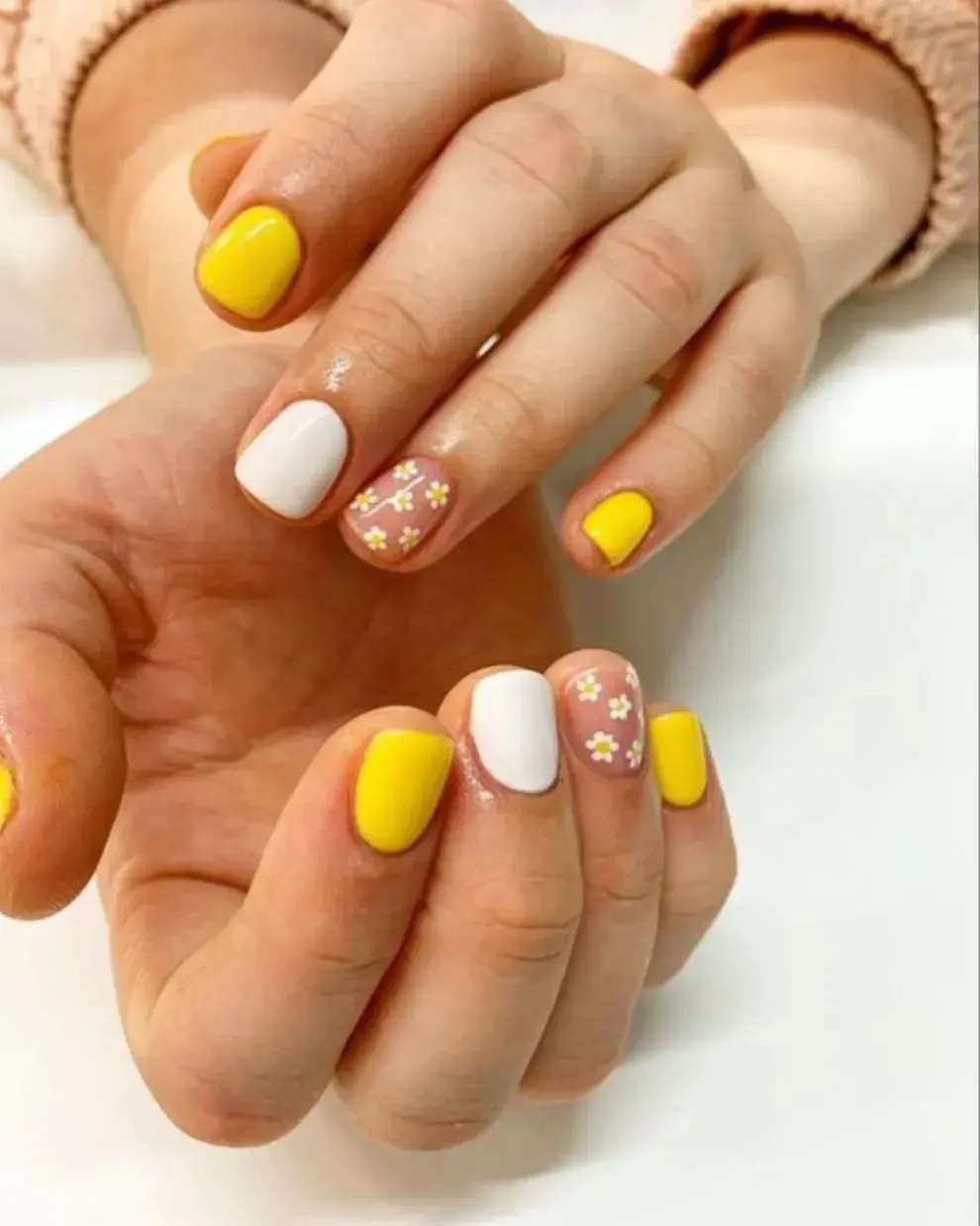  Foto de una mano de mujer con nail art de margaritas.