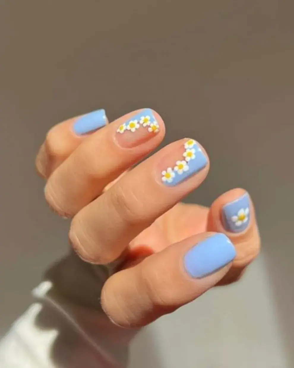 Foto de una mano de mujer con nail art de margaritas.