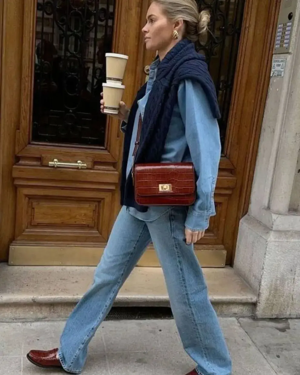 Foto de una mujer en la calle usando un suéter al hombro.