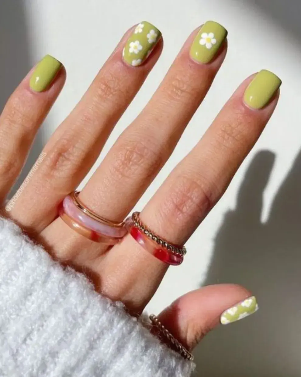 Foto de una mano de mujer con nail art de margaritas.