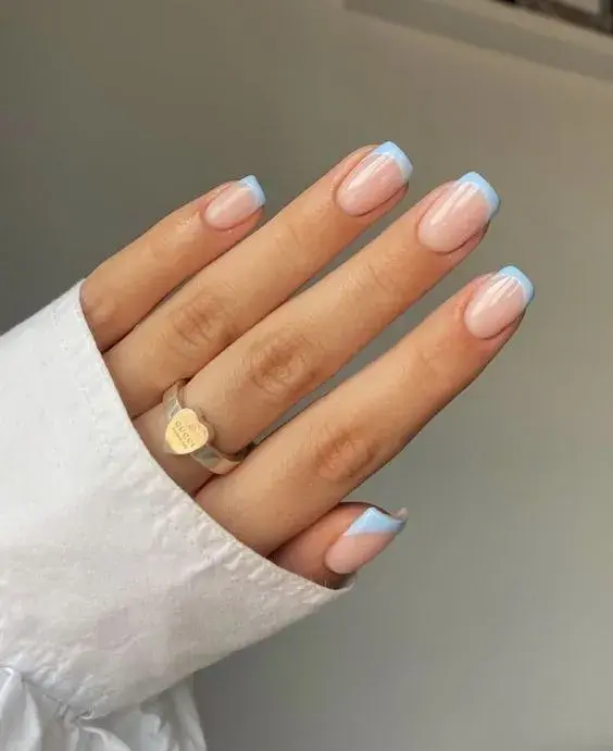  Foto de una mano de mujer con manicura francesa de color.