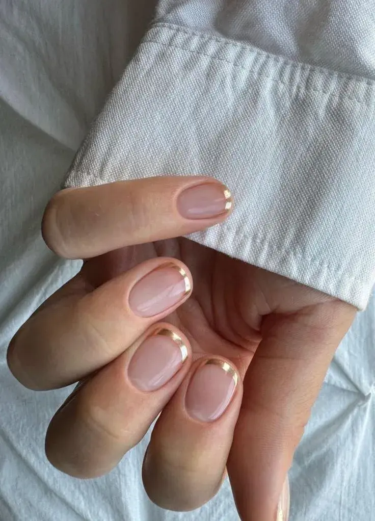 Foto de una mano de mujer con manicura francesa de color.