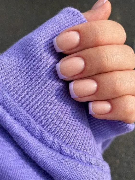 Foto de una mano de mujer con manicura francesa de color.