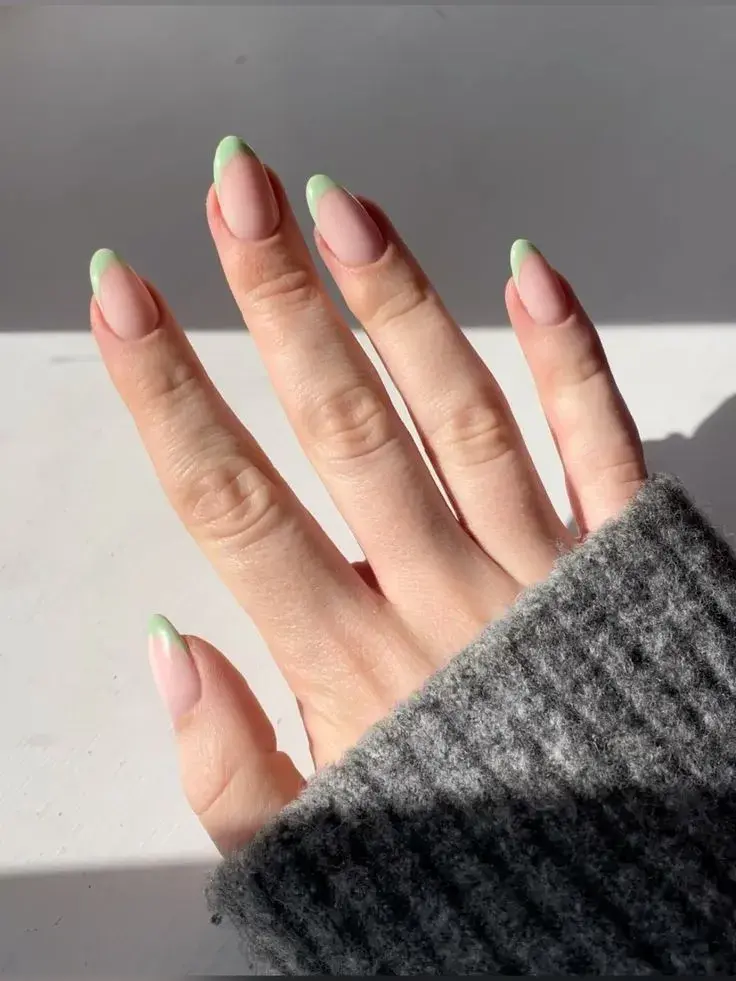 Foto de una mano de mujer con manicura francesa de color.