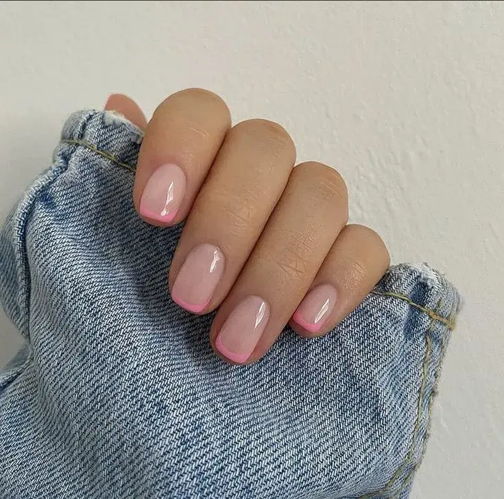 Foto de una mano de mujer con manicura francesa de color.