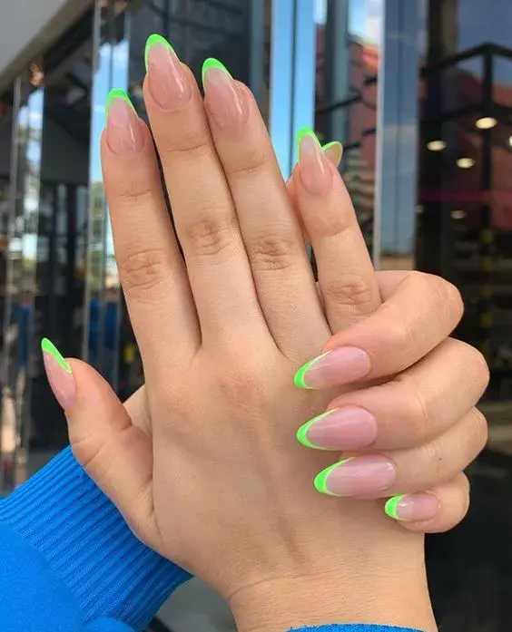 Foto de una mano de mujer con manicura francesa de color.