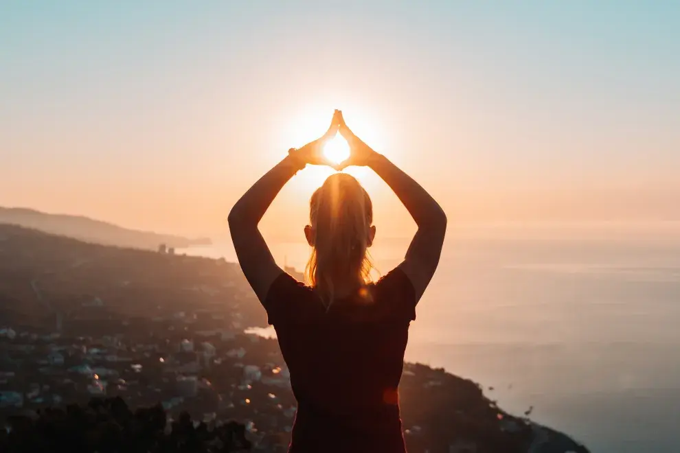 Mujer haciendo una pose de yoga en un atardecer