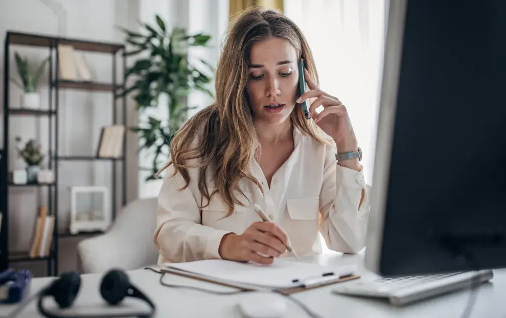 Una mujer trabajando mientras habla por teléfono