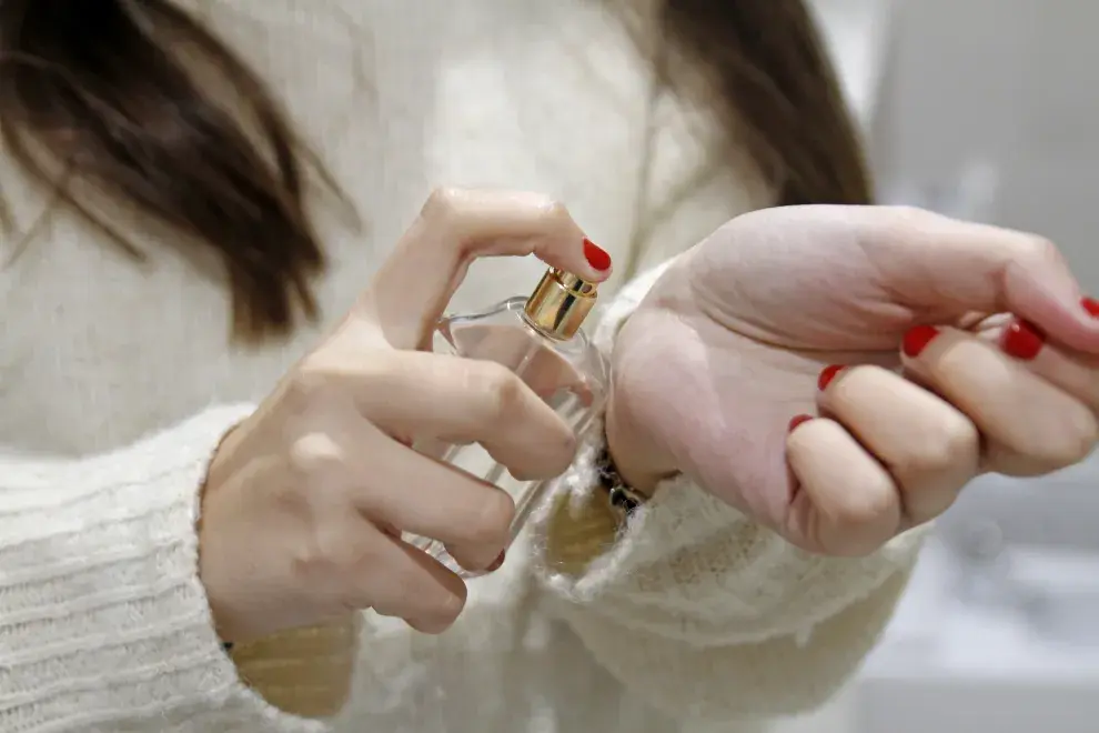 Una mujer poniendose perfume en la muñeca