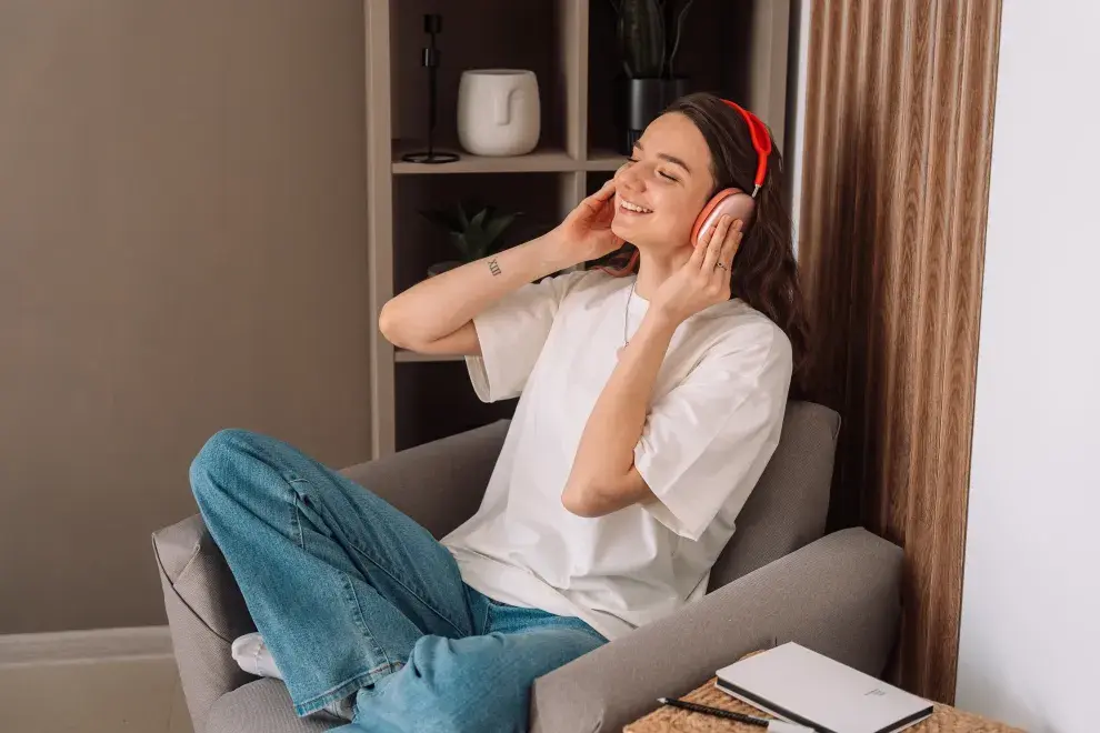 Una mujer escuchando musica desde sus auriculares en el sillón de su casa