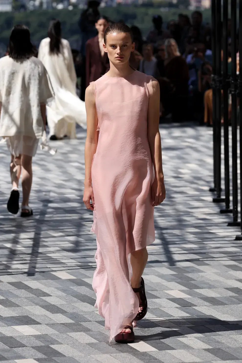 Una mujer caminando por la pasarela vestida de color rosa claro