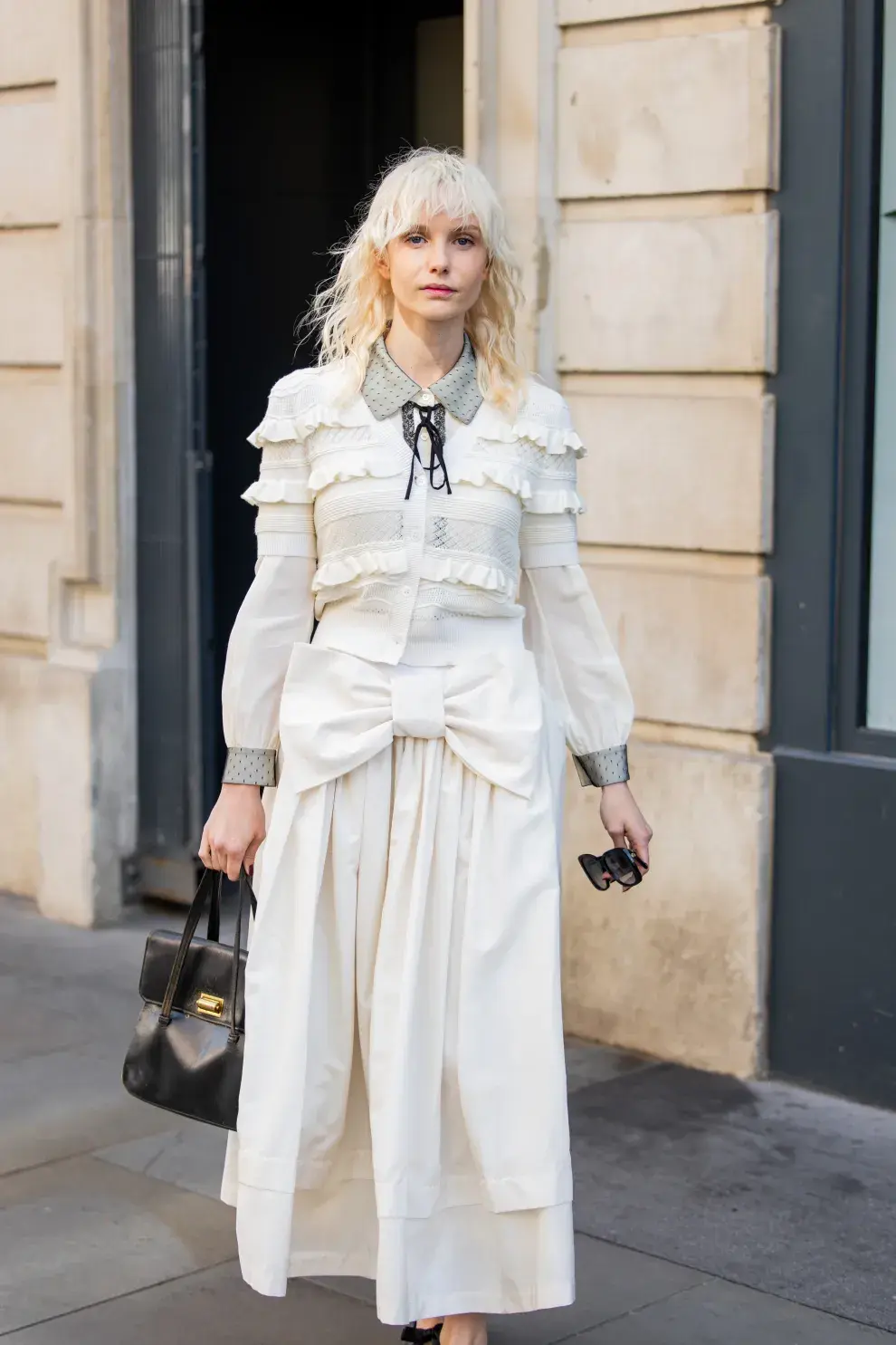 Una mujer en la semana de la moda en Londres con un look en blanco, volados y moños