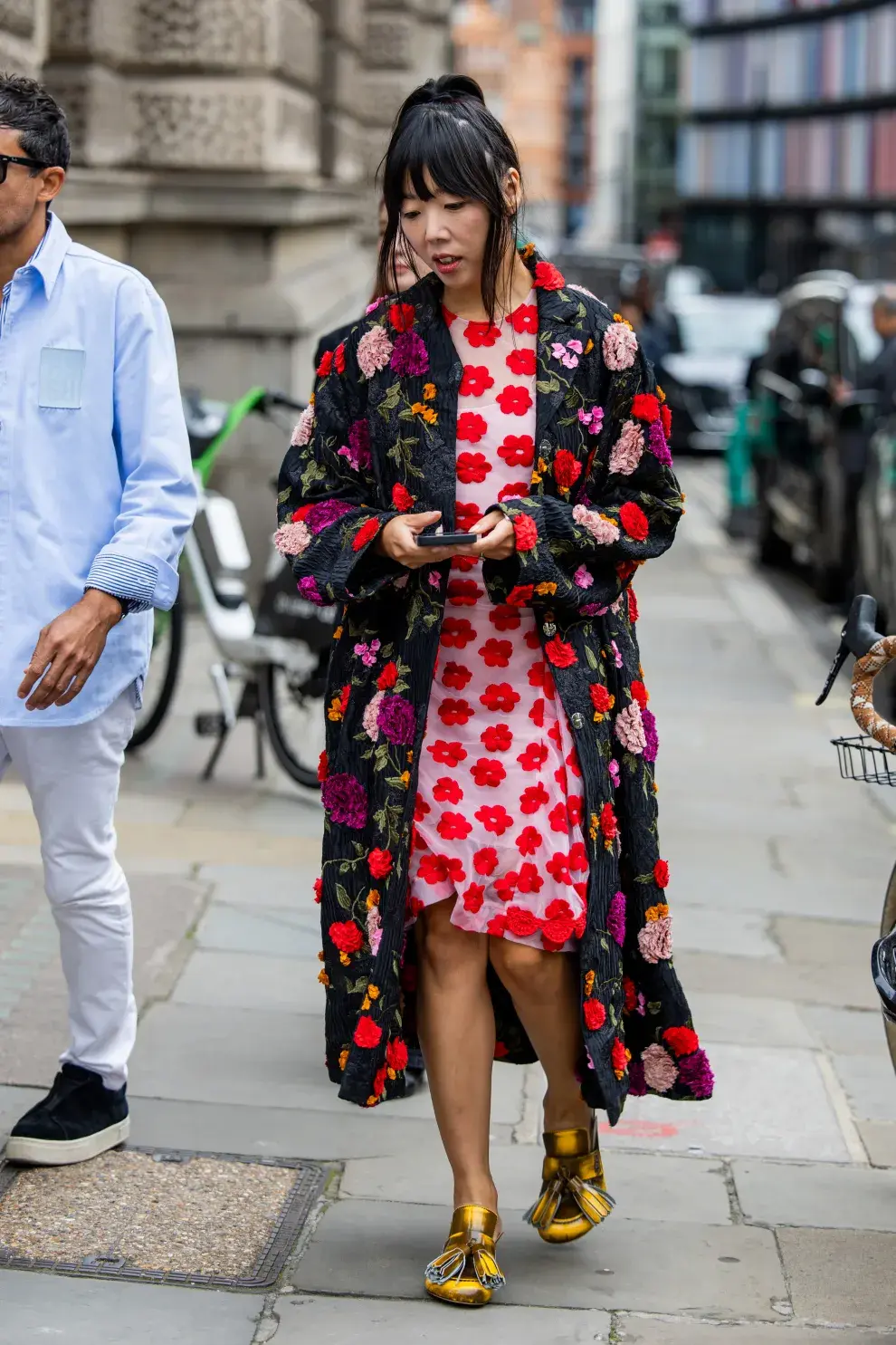 Una mujer con un abrigo y un vestido floreado caminando por Londres