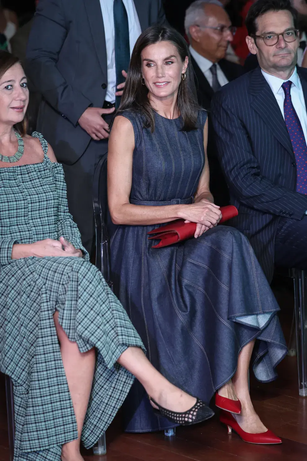 La reina Letizia usando un vestido de jean y combinando los zapatos rojos con su cartera