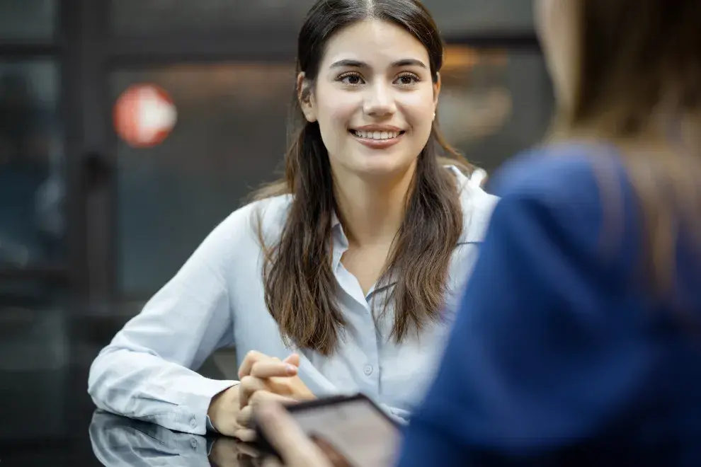 Una mujer frente a otra persona, sonriendo.