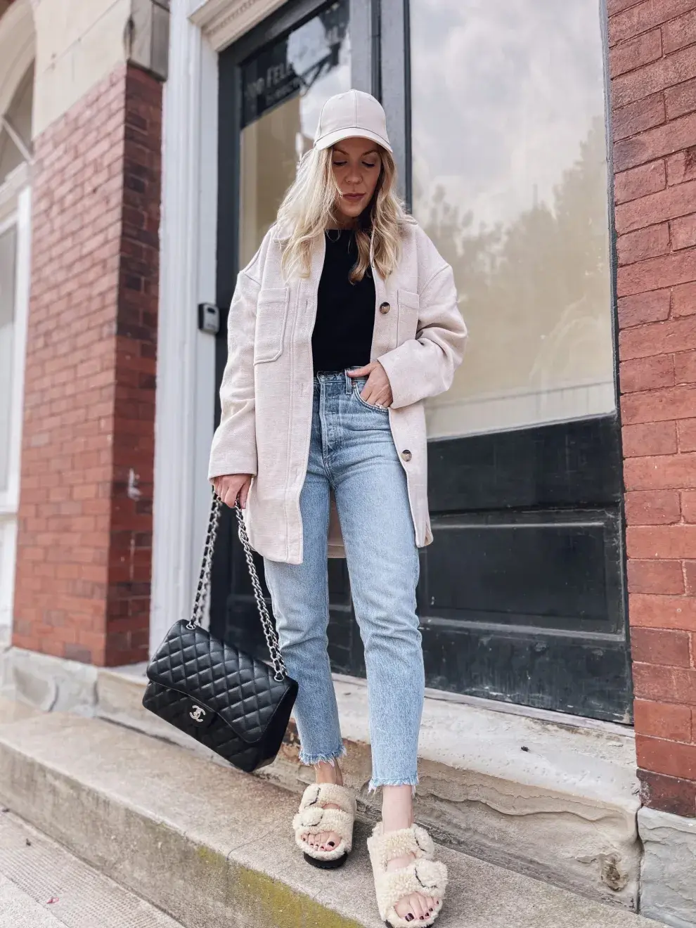 Chica posando muy canchera con una cartera negra, jeans claros y sandalias Birkenstock 