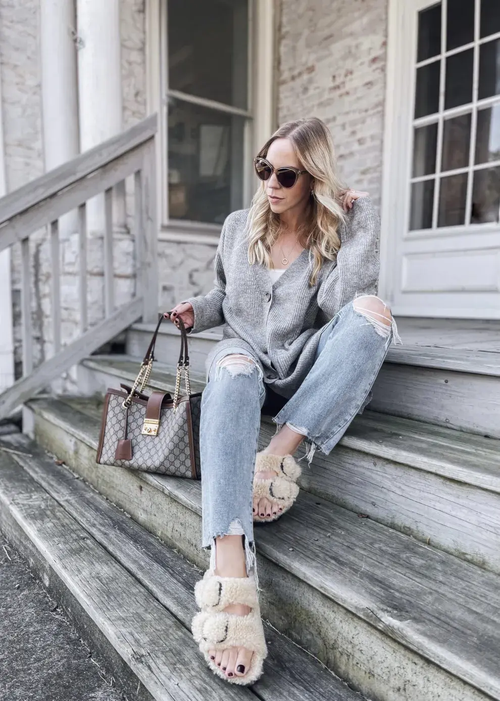 chica posando sentada en escaleras con sandalias Birkenstock, jean y sweater gris 