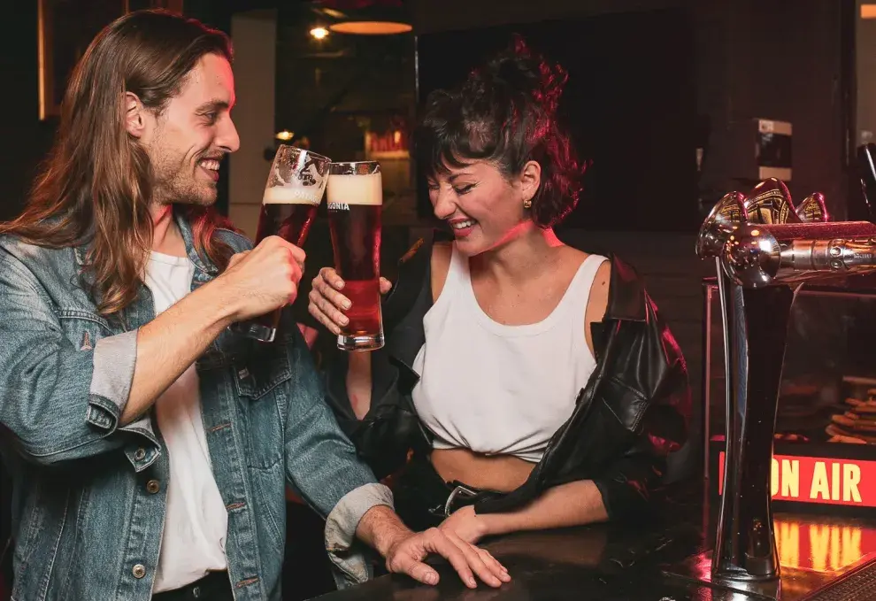 Pareja brindando con cerveza y riendo.