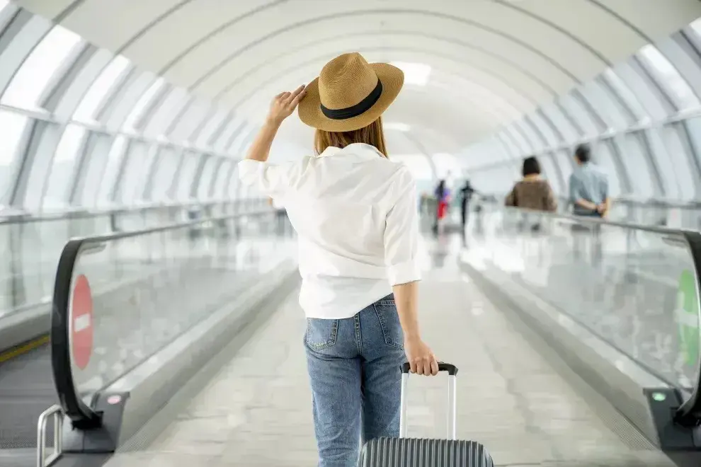 Una mujer caminando por el aeropuerto con una valija