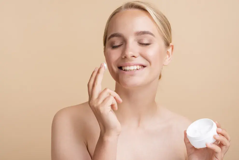 Foto de una mujer poniéndose crema hidratante en el rostro.