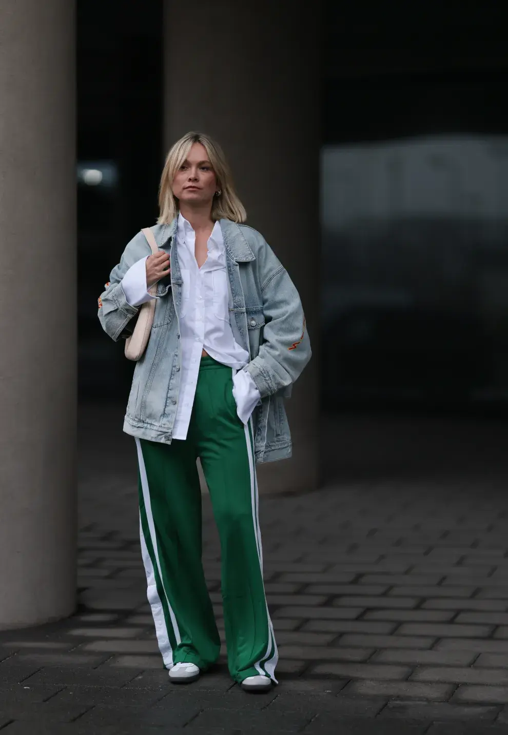 Una mujer posando con un jogging verde con una campera de denim y camisa blanca