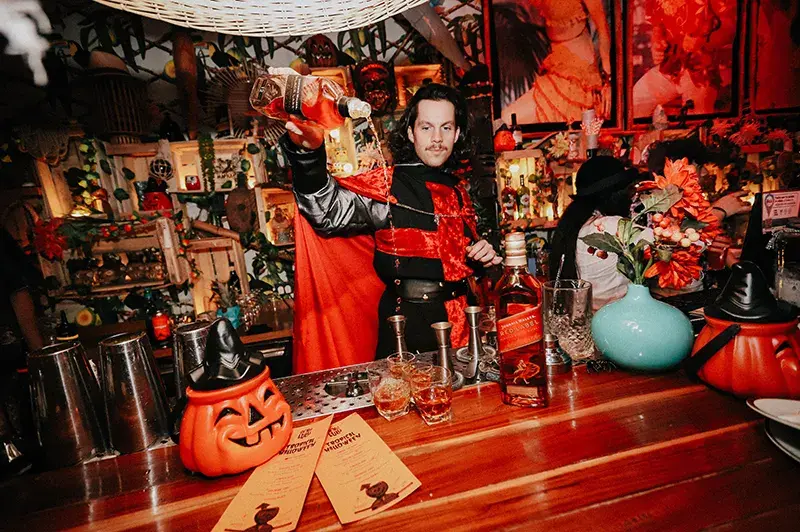 Un bartender sirviendo un trago, ambientado en Halloween.