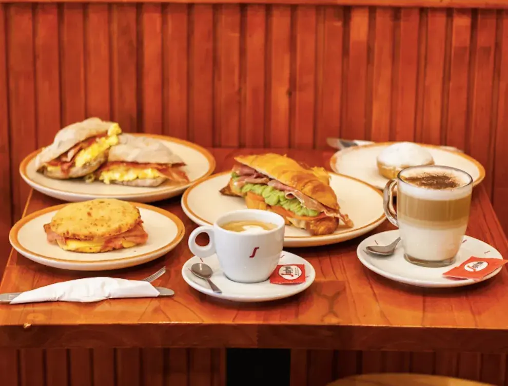 Una mesa repleta de comida. Café y sandwich