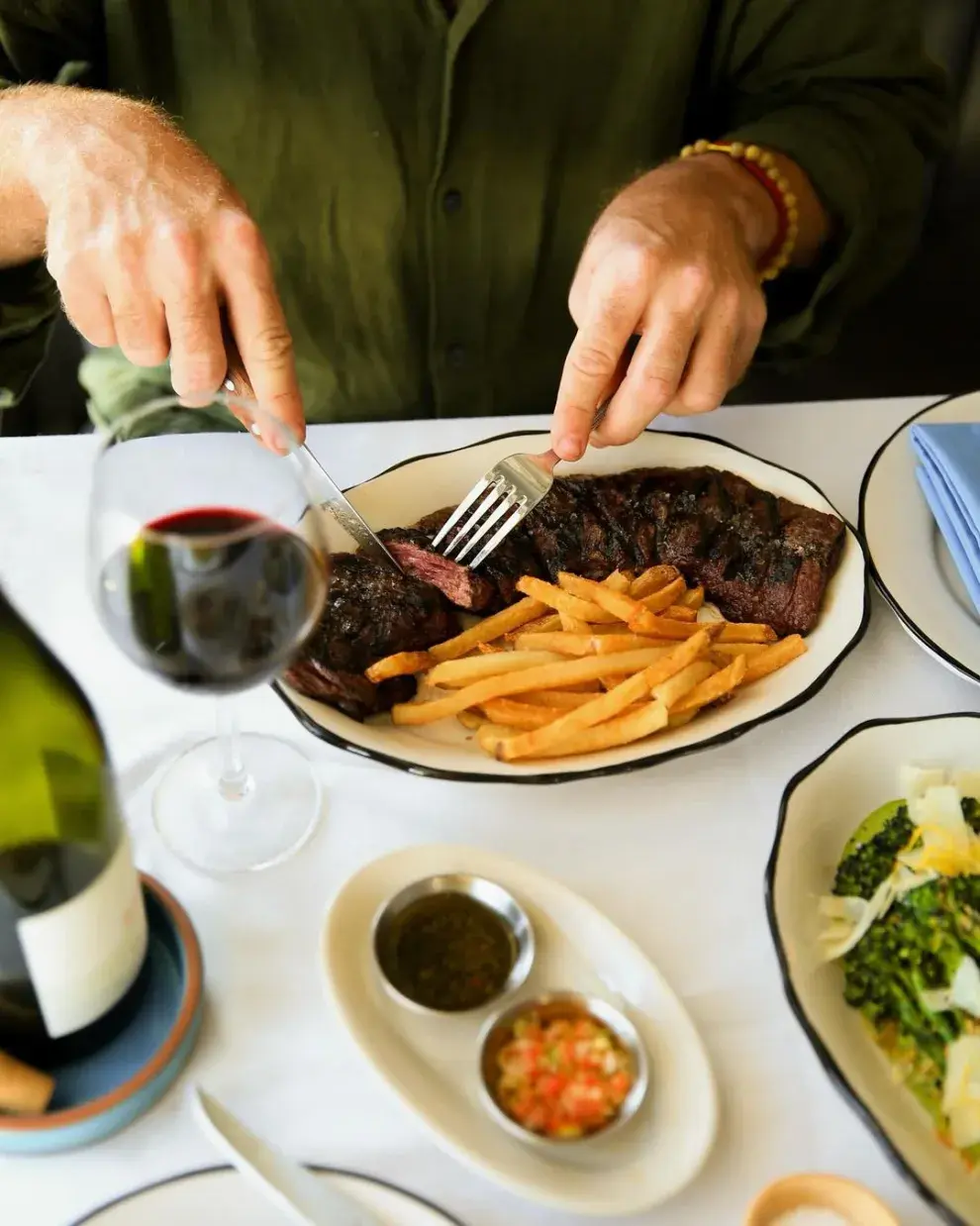 Un comensal frente a un plato de entraña con papas fritas.