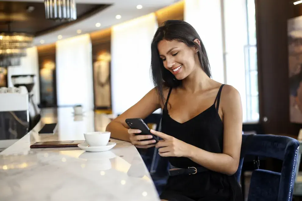 Mujer con celular en un bar