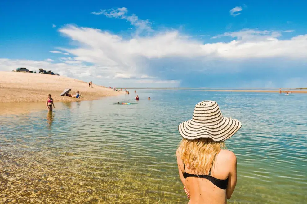 Una mujer en la playa de espaldas con un sombrero