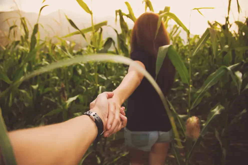 Una mujer de espaldas tomando de la mano a un varón.