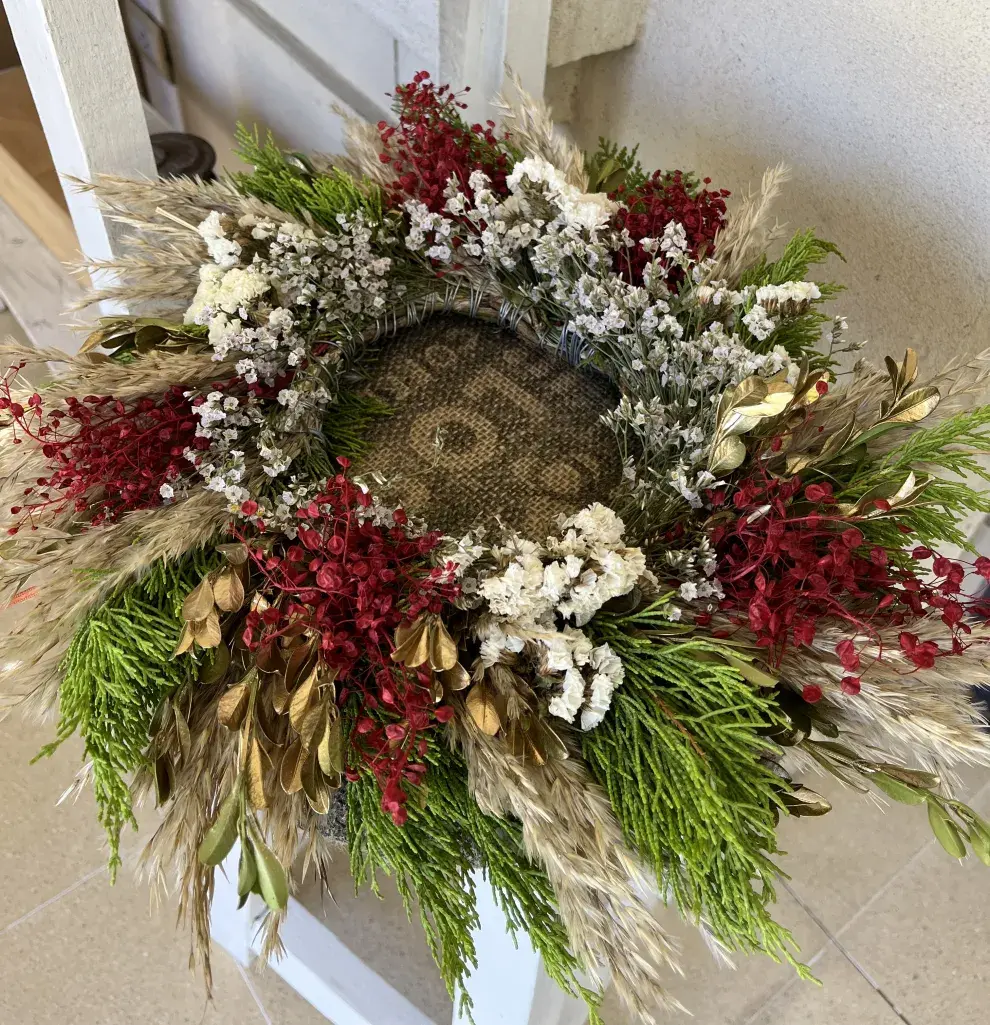 Corona de hojas de pino con flores y detalles dorados