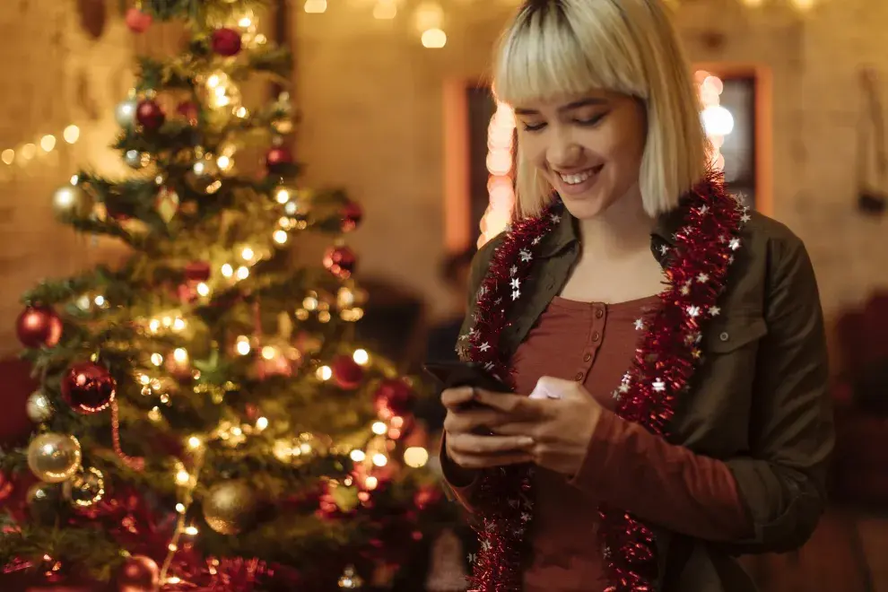 mujer con celular en Navidad