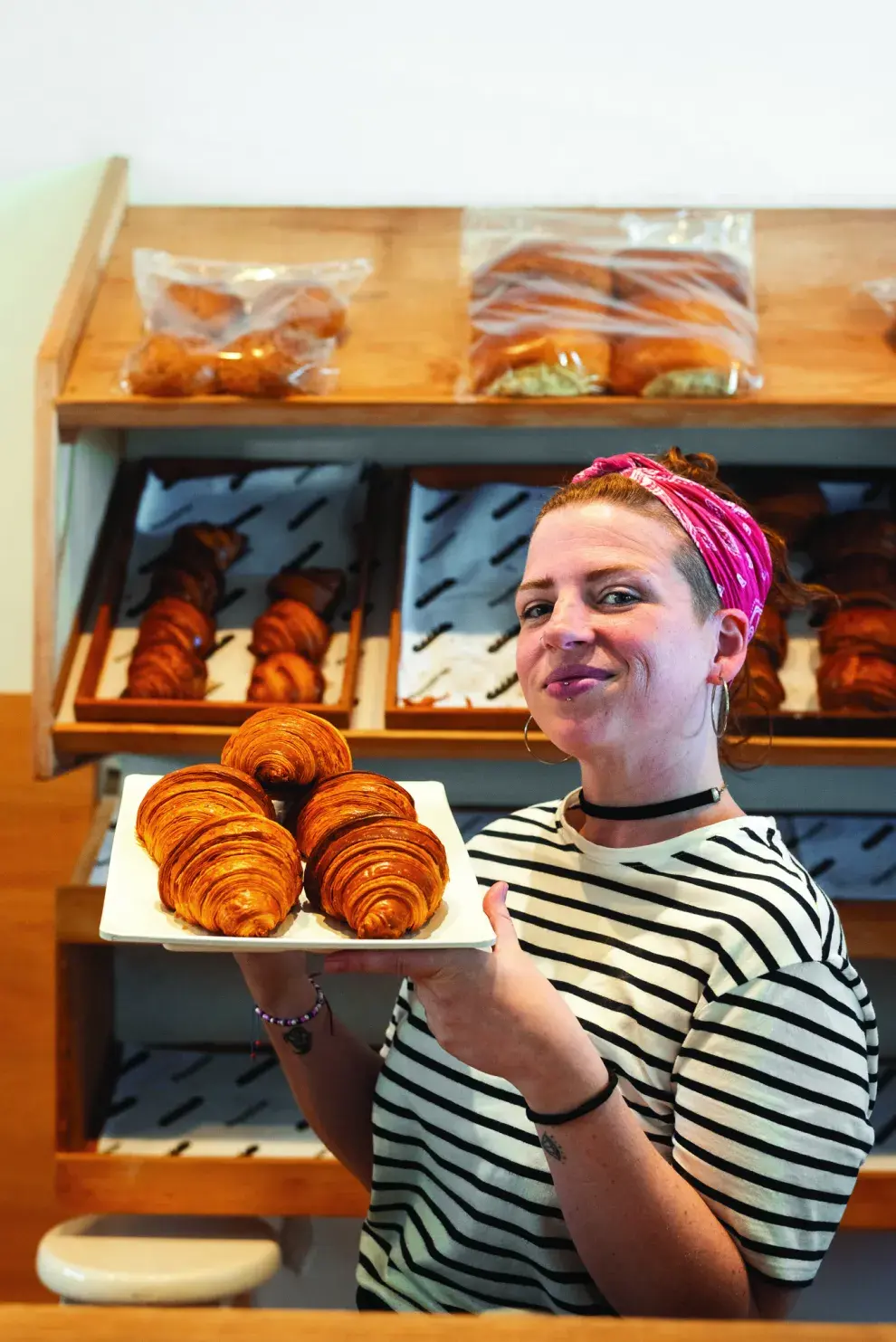 Una chica mostrando una bandeja con croissants.